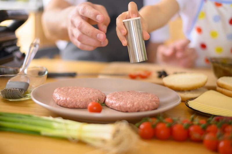 Ένα παιδάκι ρίχνει καρυκεύματα σε μπιφτέκι